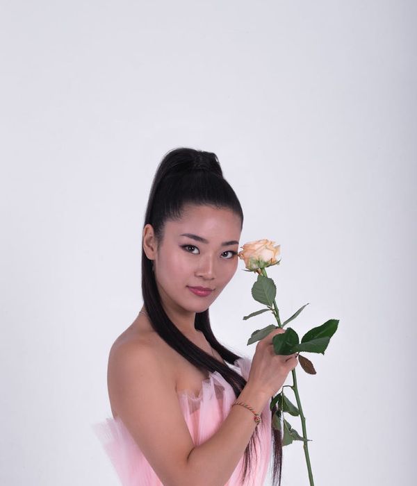 Woman in a dynamic and calm cardio pose against a dark background with pink light.